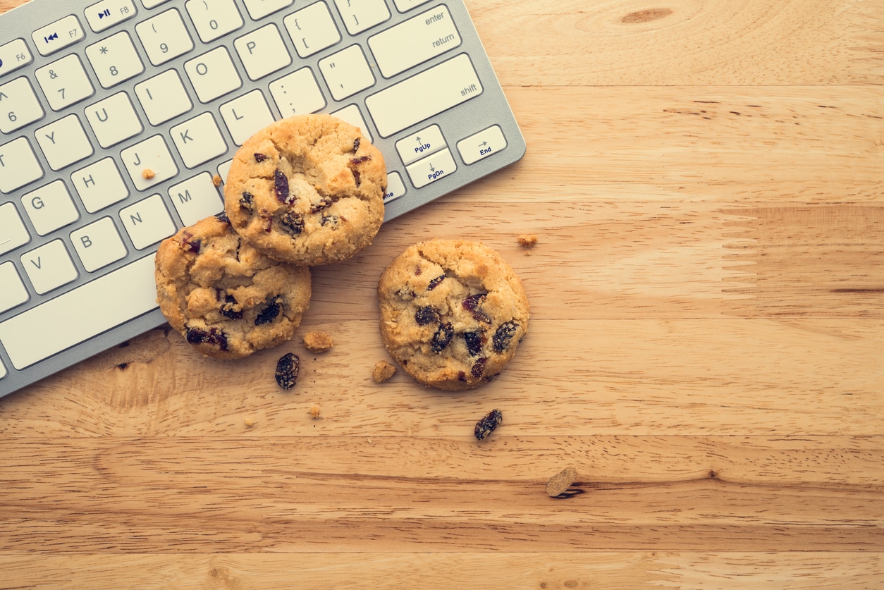Flat lay of white chocolate chip cookies on keyboard computer on wooden table background copy space. Cookies website internet homepage policy accepted or blocks concept. Third party cookie deprecation. 