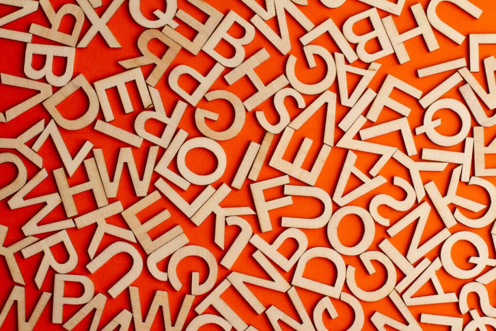 top view closeup detail macro of many wooden cut small alphabet letters on orange background