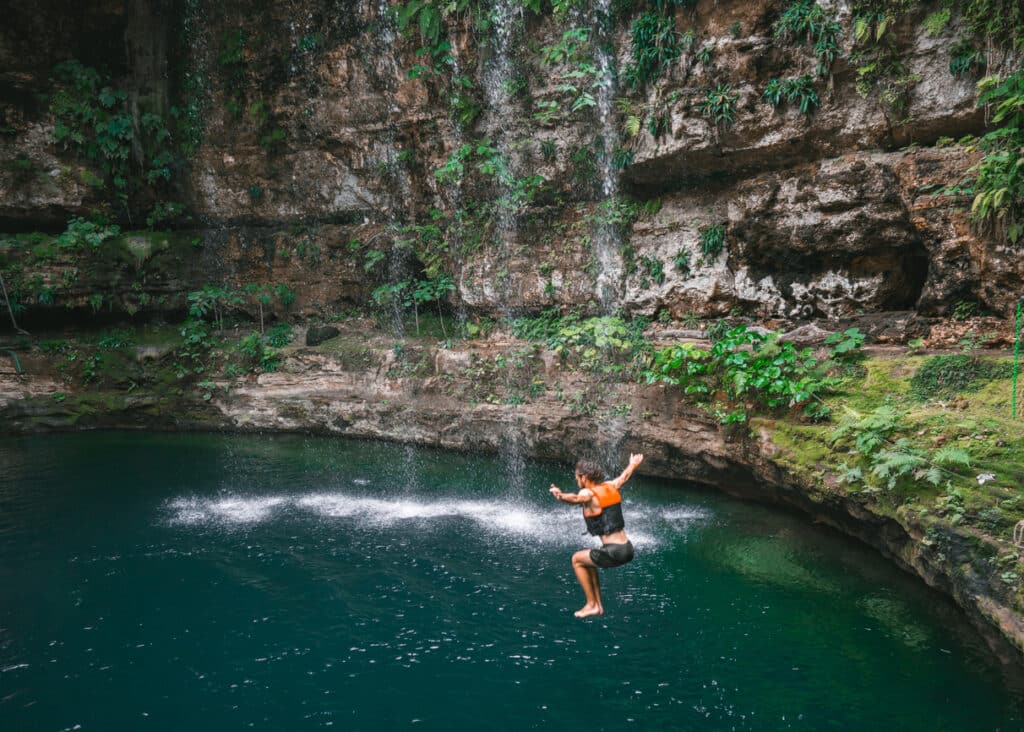 Young Caucasian man jumping into Cenote in Yucatan, Mexico