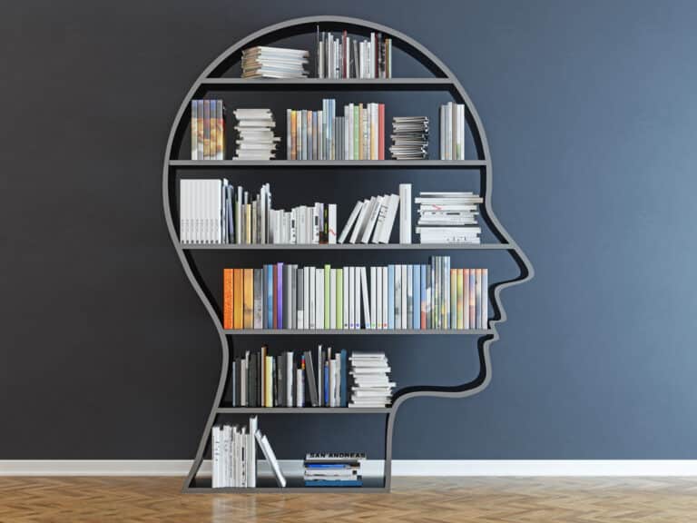 Head with a bookshelf in front of black wall representing knowledge management technology