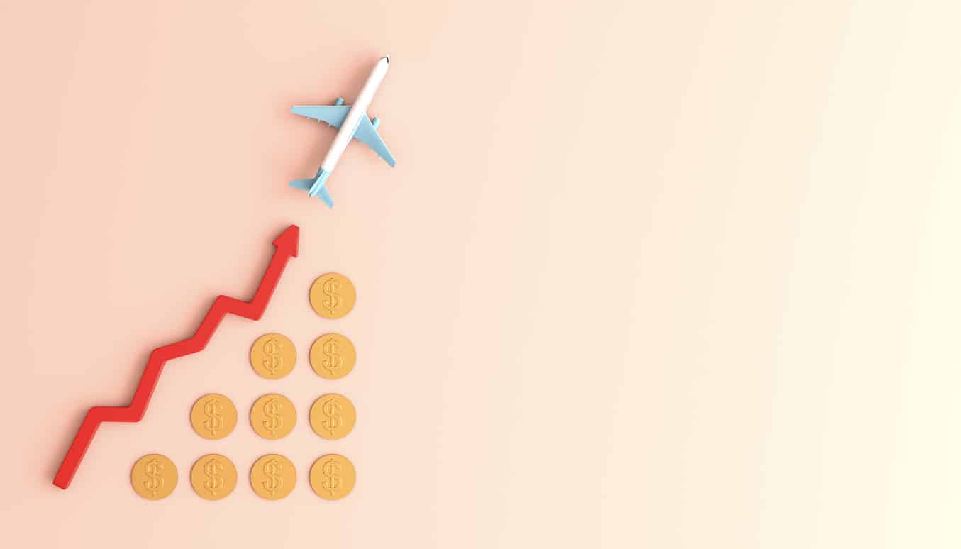 A toy airplane ascending over a rising red arrow chart composed of gold coins, symbolizing the concept of dynamic pricing in the airline industry where fares fluctuate with demand. 