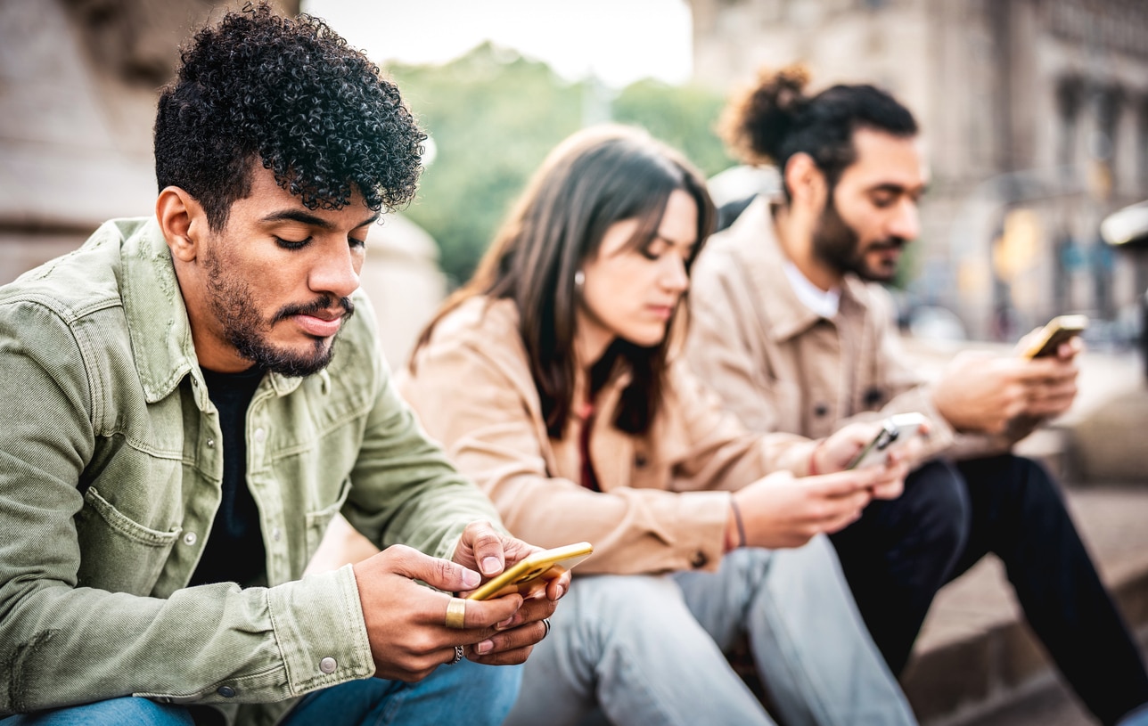 A group of people with concerned expressions, staring at their phones, symbolizing the spread of misinformation and the erosion of trust in the digital age.