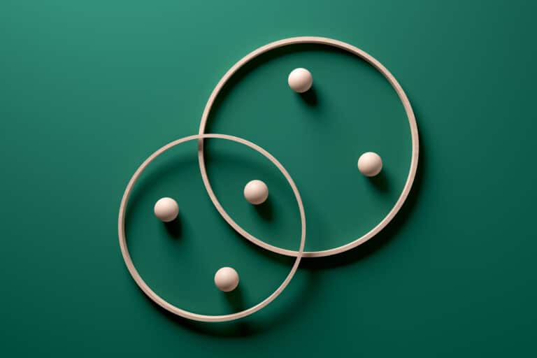 Two wooden rings interlocking with balls inside them on a green background. This image symbolizes the combination of traditional search methods with semantic understanding in hybrid search.