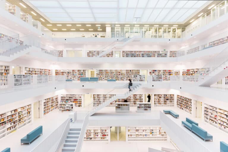 Large white library with many rows of bookshelves and a modern design with glass windows. [Large language models and search engines working together / Librarian using search engine to find information]