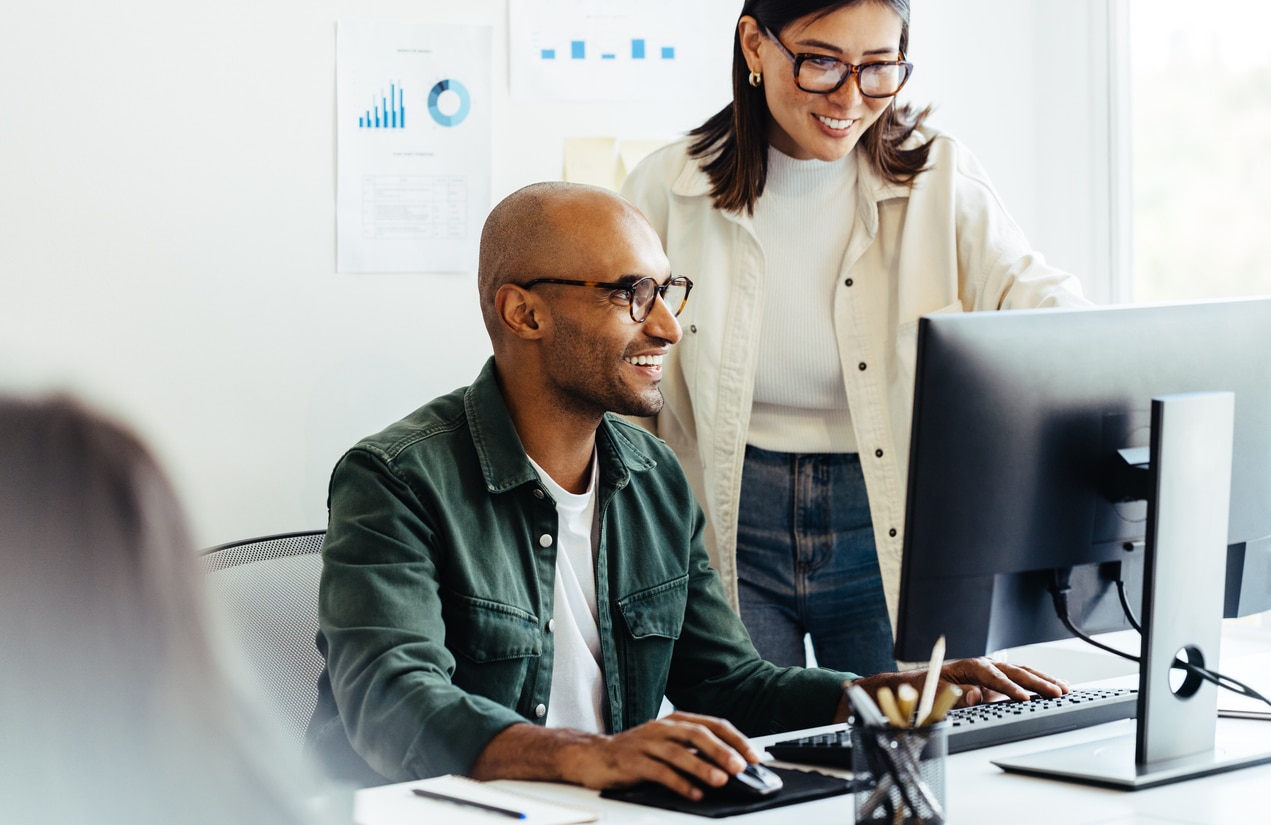 Web developers using a computer together in a creative office. Two business people working on a new software developing project in an office. Represents effective AI-powered product discovery.