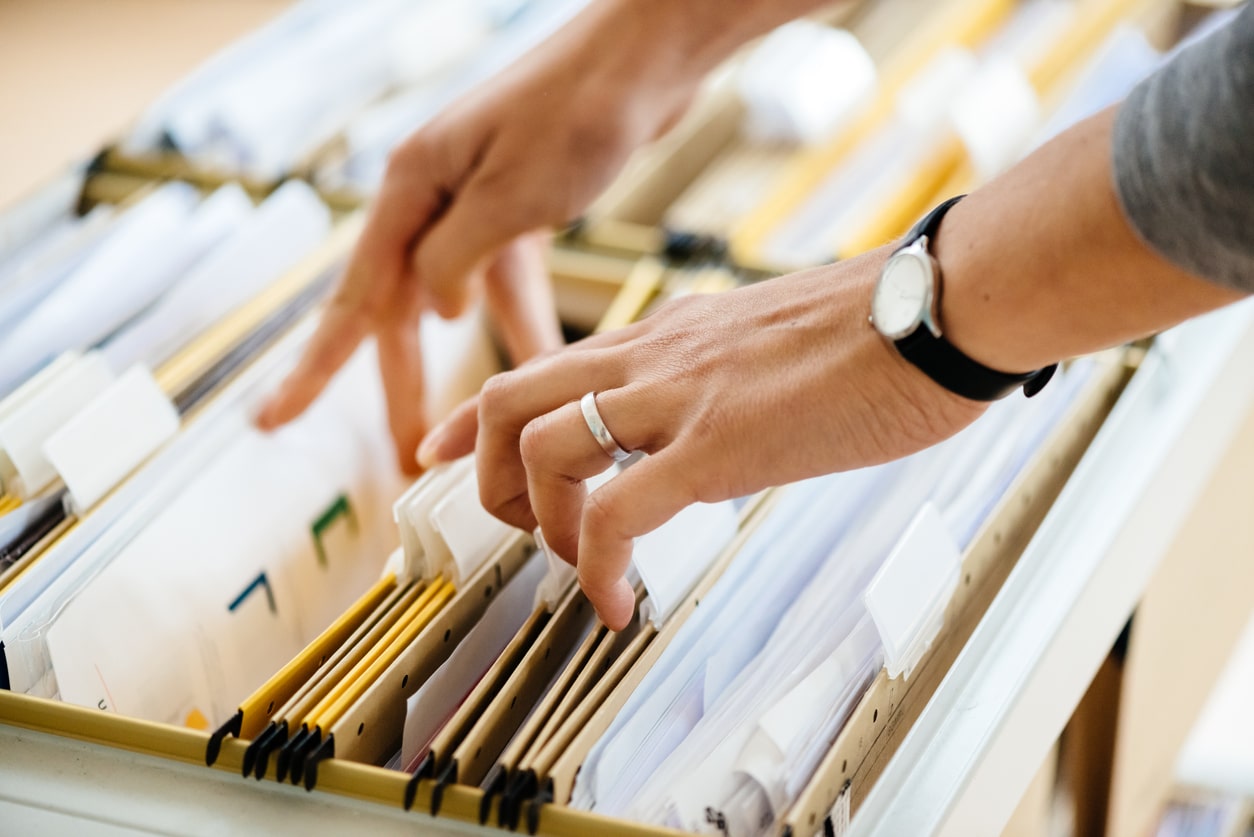 Close-up of hands searching in a file cabinet