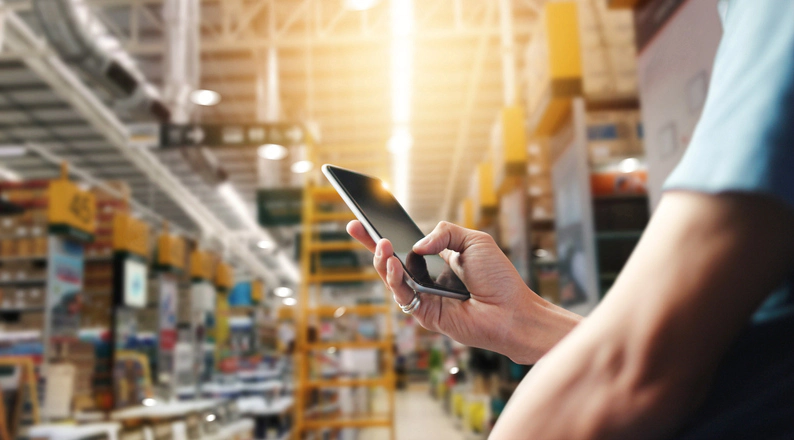 Person mit Smartphone im Lagerhaus